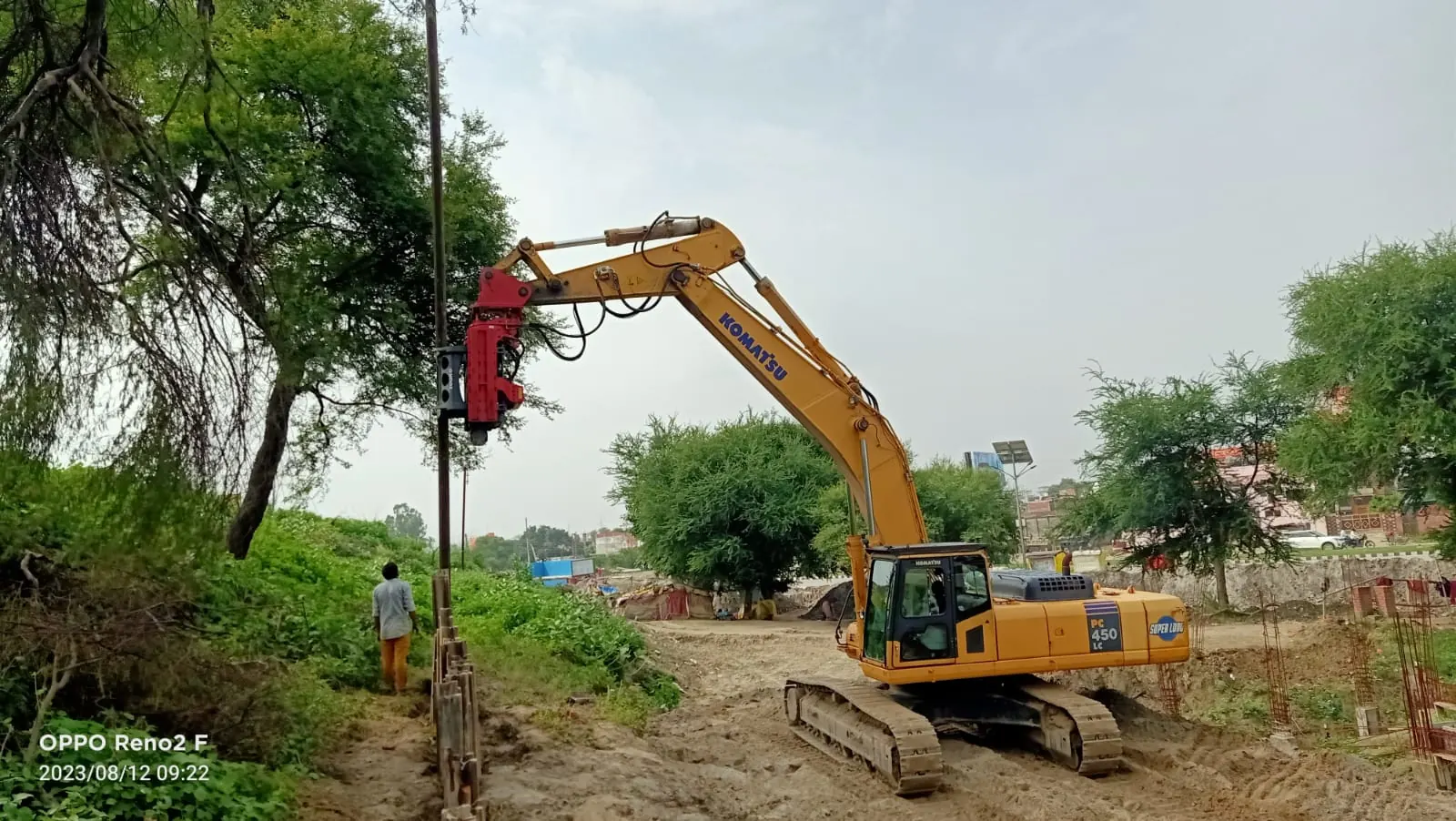Pile driving beside a tree line, Uttar Pradesh, 2026, infrastructure work by M/S VKJJVBBNINFRA